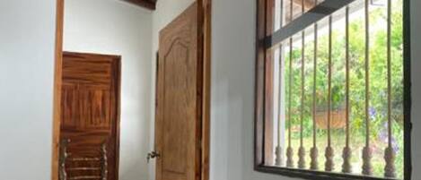 A hallway with a wooden door and a window with a metal grille.