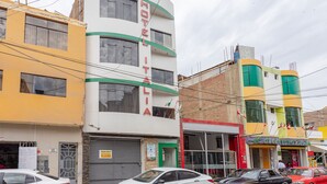 Un hotel de varios pisos con un llamativo letrero que dice "HOTEL ITALIA", con balcones y un diseño moderno.