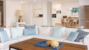 A modern living room with a white sofa, patterned cushions, a wooden coffee table, and a blue tray. - Private Pool, Hotel Services & Steps to Beach (San Jose del Cabo)