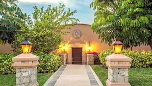 A pathway leading to a building entrance with stone pillars and wall-mounted lights. - Private Pool, Hotel Services & Steps to Beach (San Jose del Cabo)