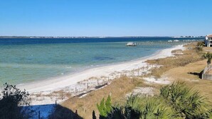 A coastal beach with clear waters, a sandy shore, and a distant pier. - Palm Beach Oasis - Soundfront - Quiet (Pensacola Beach)