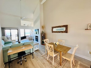 Un salón amplio con sofá, una mesa de comedor con sillas, un televisor montado en la pared y una chimenea.