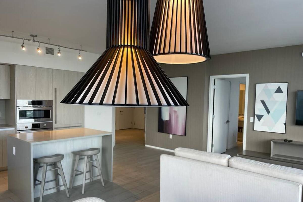 A modern kitchen with a central island, bar stools, and pendant lighting.