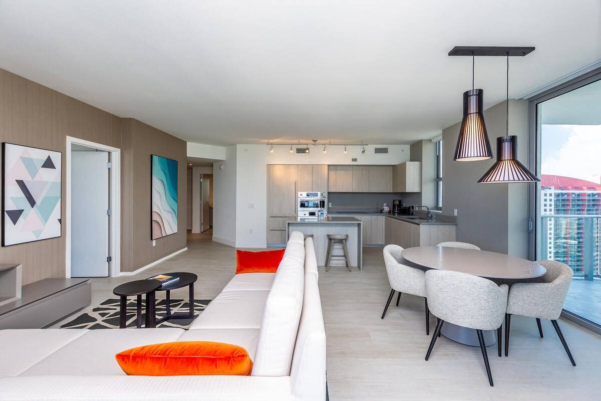 A modern apartment with a living area, dining space, kitchen, and a balcony with a city view.