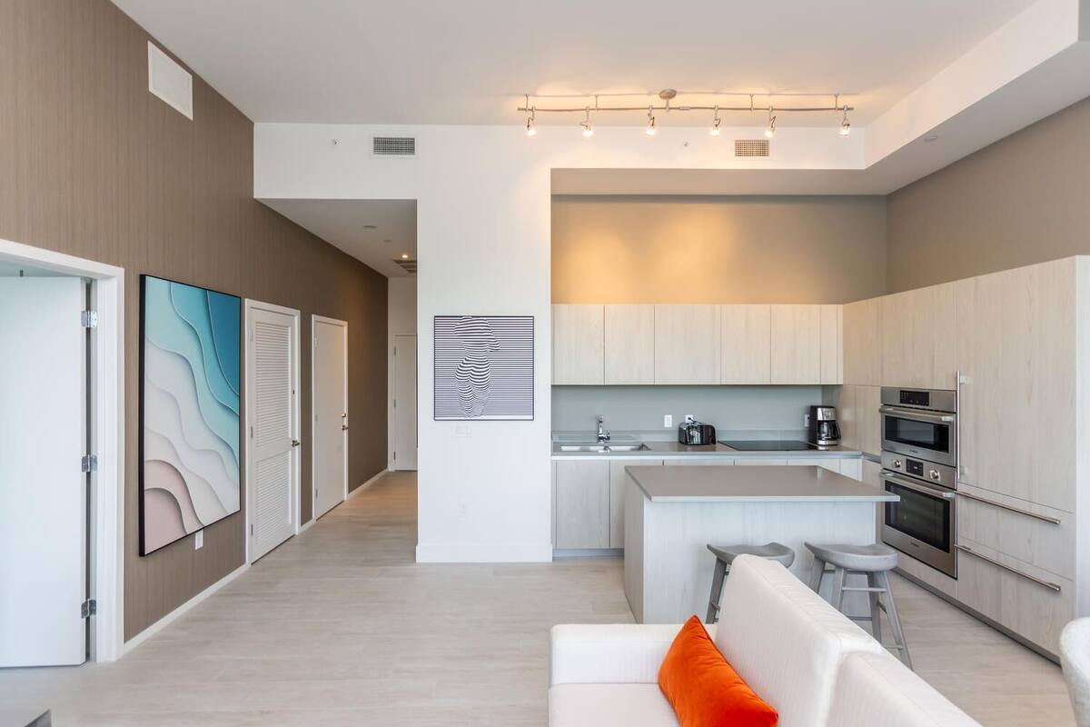 A modern kitchen with white cabinets, a central island, and built-in appliances.