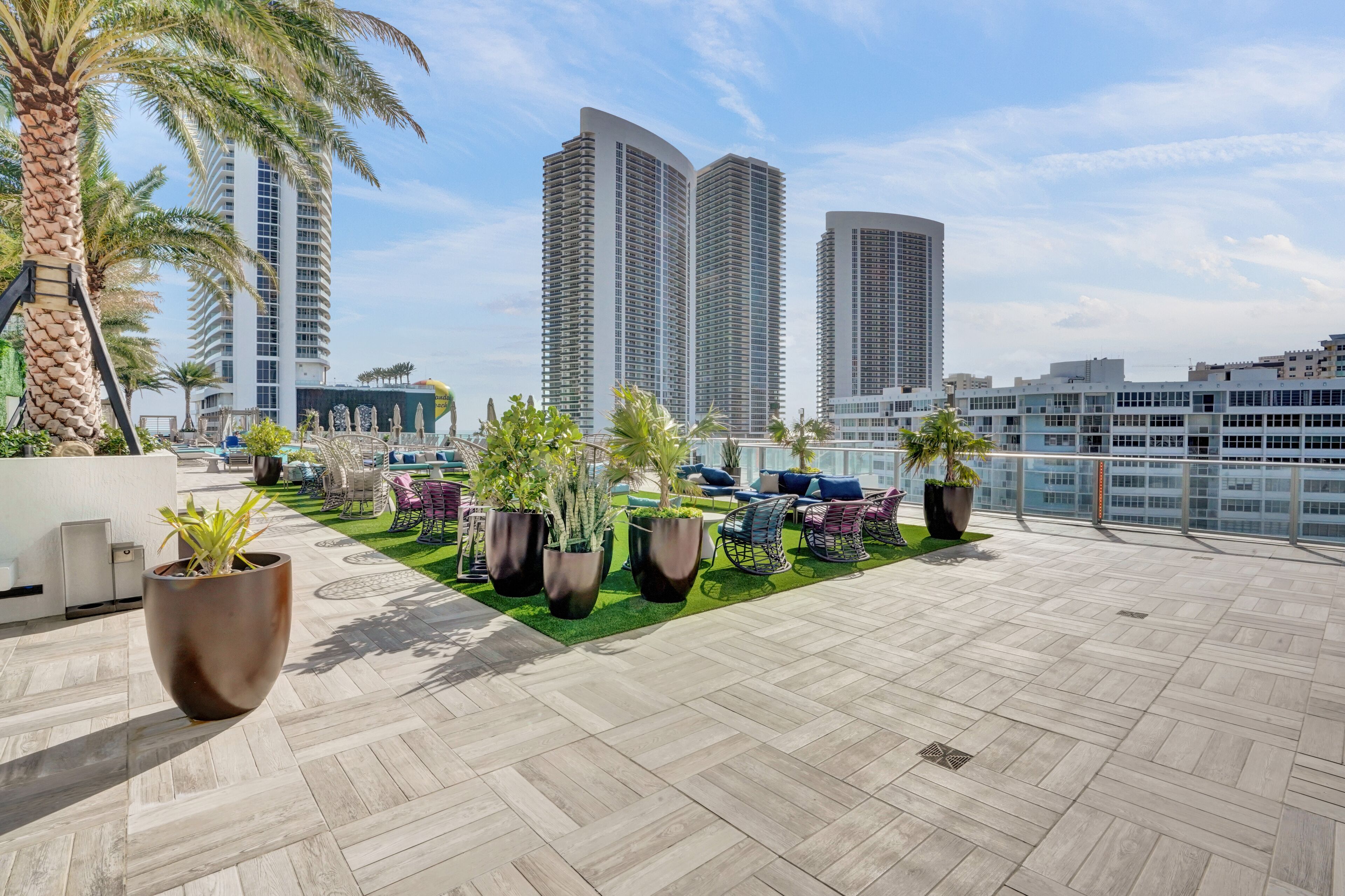 A rooftop terrace with potted plants, outdoor seating, and a view of tall buildings.