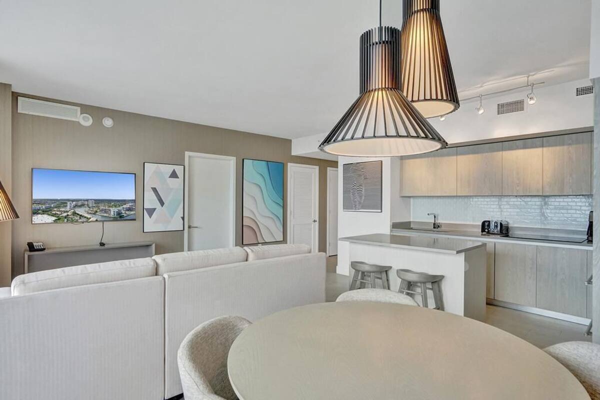 A modern living room with a sofa, a dining table, and a kitchen area with a bar.