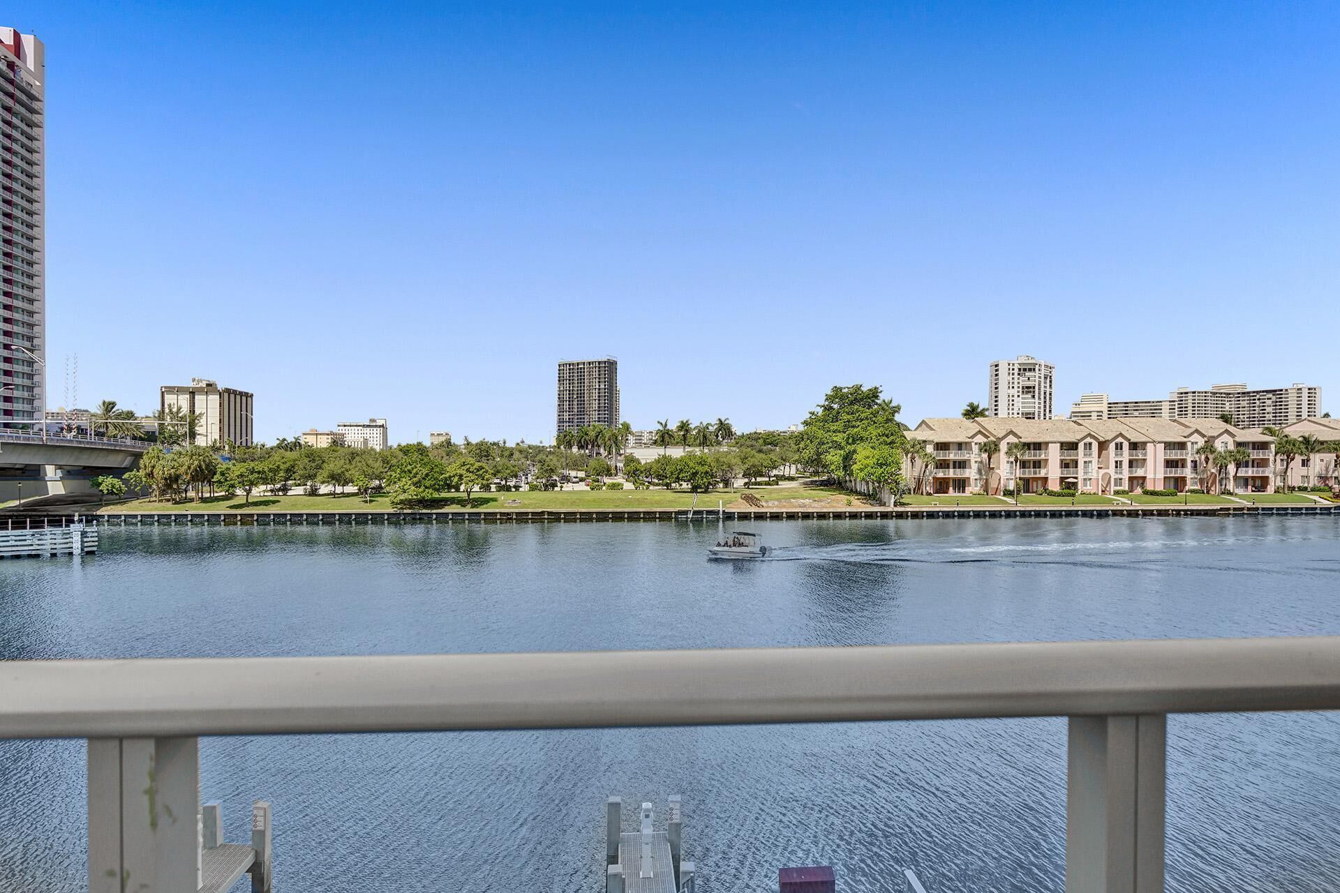 A waterfront view with a river, buildings, and a bridge.