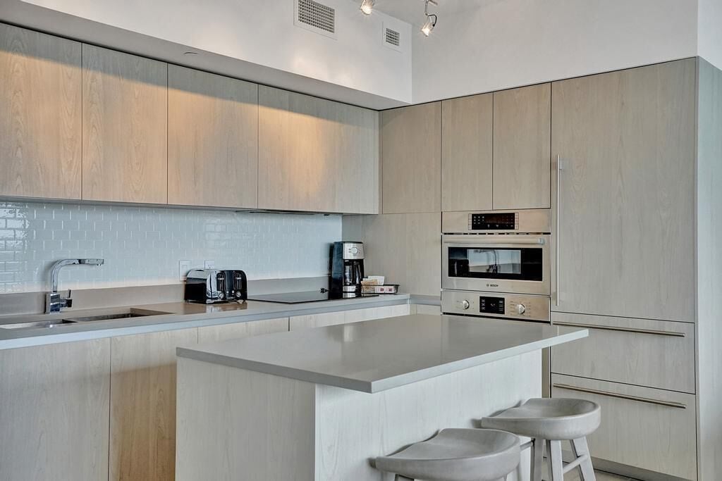 Et moderne køkken med en stor ø, integrerede hårde hvidevarer og et minimalistisk design.