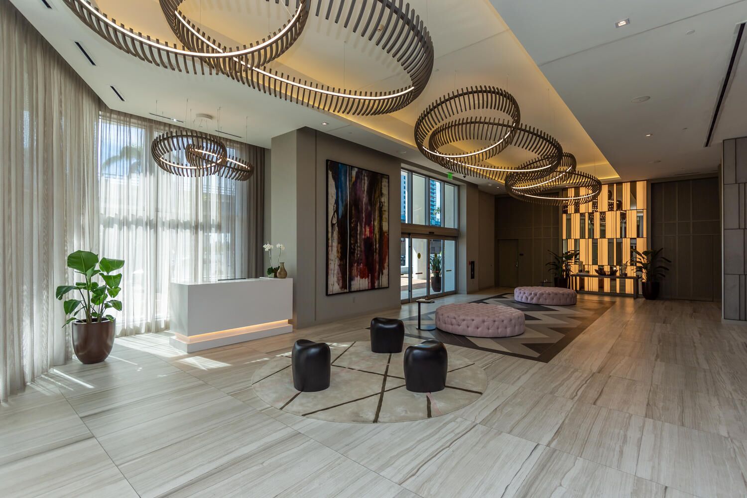 A spacious lobby with a modern design, featuring a reception desk, seating areas, and large windows allowing natural light.