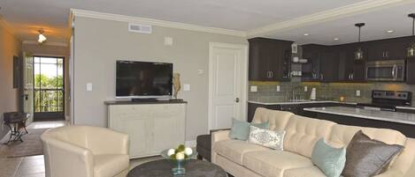 A modern living room with a beige sofa, a round coffee table, and a flat-screen TV.