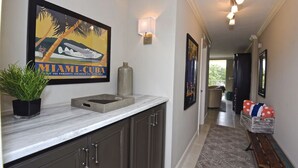 A hallway with a framed poster, a potted plant, a marble countertop, and a bench. - Renovated  Condo with Luxury Amenities in Perfect Beach Location (Marco Island)