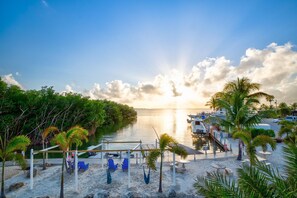 A beachside view with a dock, lounge chairs, and a calm sea at sunset. - Your Perfect Getaway in Key Largo! 🌴 Escape to Paradise in the Florida Keys! 🌊 (Key Largo)