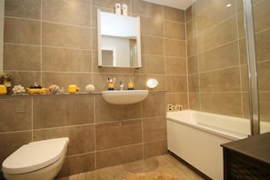 Enjoy a refreshing bath in the bathroom, featuring a bathtub, sink, and toilet.