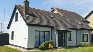 Une maison à deux étages, dotée d’un toit en pente, de grandes fenêtres et d’une pelouse bien entretenue.