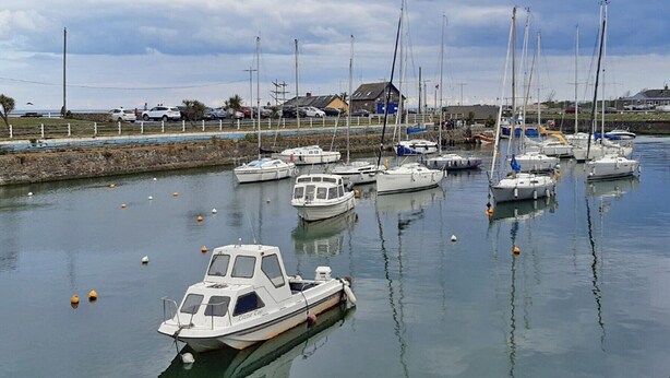 Un port de plaisance avec plusieurs bateaux amarrés, un petit bateau au premier plan et un bâtiment en arrière-plan.