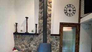 A stone fireplace with a chimney, a clock on the wall, and a door to the right. - Moon River Cottage • Loft • River Access • Fireplace • Peaceful • Near Sequoia (Three Rivers)