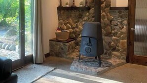 A cozy room with a stone fireplace, a large window, and a comfortable seating area. - Moon River Cottage • Loft • River Access • Fireplace • Peaceful • Near Sequoia (Three Rivers)
