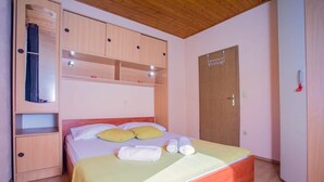 A bedroom with a bed, wooden wardrobe, and a door. - Natura-Gata,Omiš-small stone apartman with swimming pool (Gata)