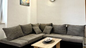 A modern living room with a sectional sofa, a wooden coffee table, and a wall-mounted light fixture. - Natura-Gata,Omiš-small stone apartman with swimming pool (Gata)