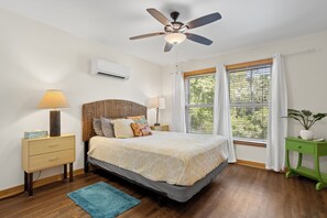 A bedroom with a bed, a nightstand, a green side table, a ceiling fan, and a window with curtains. - Pool, Boat Ramp, Games, Pass Christian Waterfront Sleeps 18 Guests 6 Bedrooms  (Pass Christian)