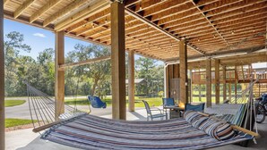 A hammock under a wooden pergola with a view of a park and outdoor seating area. - Pool, Boat Ramp, Games, Pass Christian Waterfront Sleeps 18 Guests 6 Bedrooms (Pass Christian)