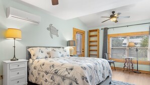 A bedroom with a bed, bedside tables, a ceiling fan, a window with blinds, and a wall-mounted air conditioner. - Pool, Boat Ramp, Games, Pass Christian Waterfront Sleeps 18 Guests 6 Bedrooms (Pass Christian)