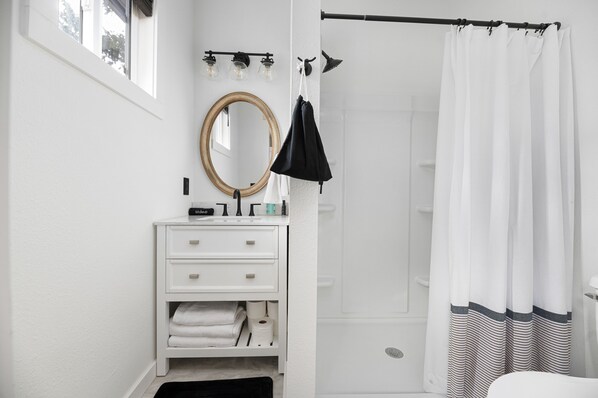 A bathroom with a white vanity, a mirror, a towel rack, and a shower curtain. - Beautiful Modern/Rustic Cottage in the heart of Lead!!! (Lead)