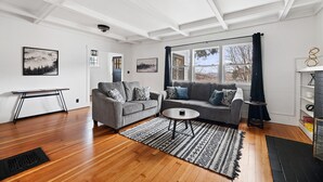 Ein modernes Wohnzimmer mit zwei grauen Sofas, einem Couchtisch und einem großen Fenster mit Vorhängen.