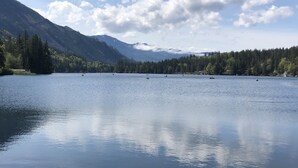 Un lac paisible où l’on peut naviguer, entouré de forêts denses et de montagnes.