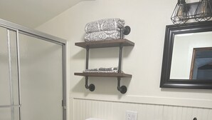 Une salle de bain équipée de toilettes, d’une douche, d’un lavabo et d’un miroir.