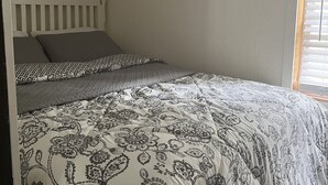 Une chambre à coucher avec un lit, une fenêtre avec des stores et un plafond blanc.