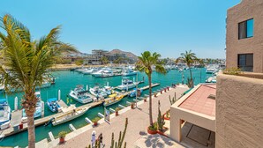 A marina with boats docked, palm trees, and a building with a red roof. - Marina View Open Studio Suite on Marina 645SF walk everywhere! NEW Rooftop Pool (Cabo San Lucas)