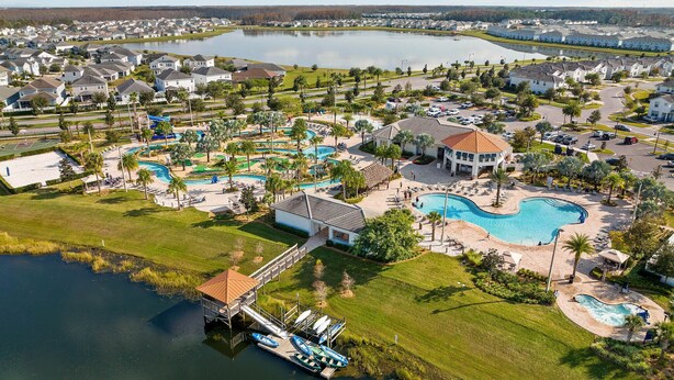 Una zona residencial con una piscina grande, un muelle con barcos y una cancha de tenis.