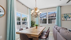 Un comedor con mesa de madera, sillas, una lámpara de araña y un sofá.