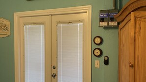 A bedroom with a bed, a wooden wardrobe, a door with a window, and a wall-mounted clock.