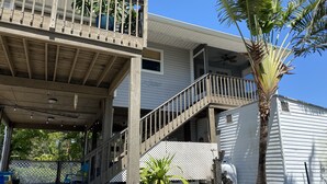 A two-story house with a balcony, a staircase, and a palm tree.