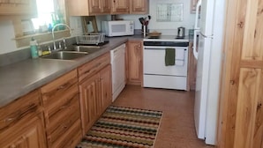 Una cocina con armarios de madera, microondas, estufa y refrigerador.