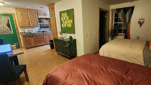 Un dormitorio con cama, un escritorio con ordenador portátil, cómoda y un mueble verde.