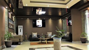 A modern lobby with a sofa set, a coffee table, and potted plants. - Hera Hotel (Kampala)