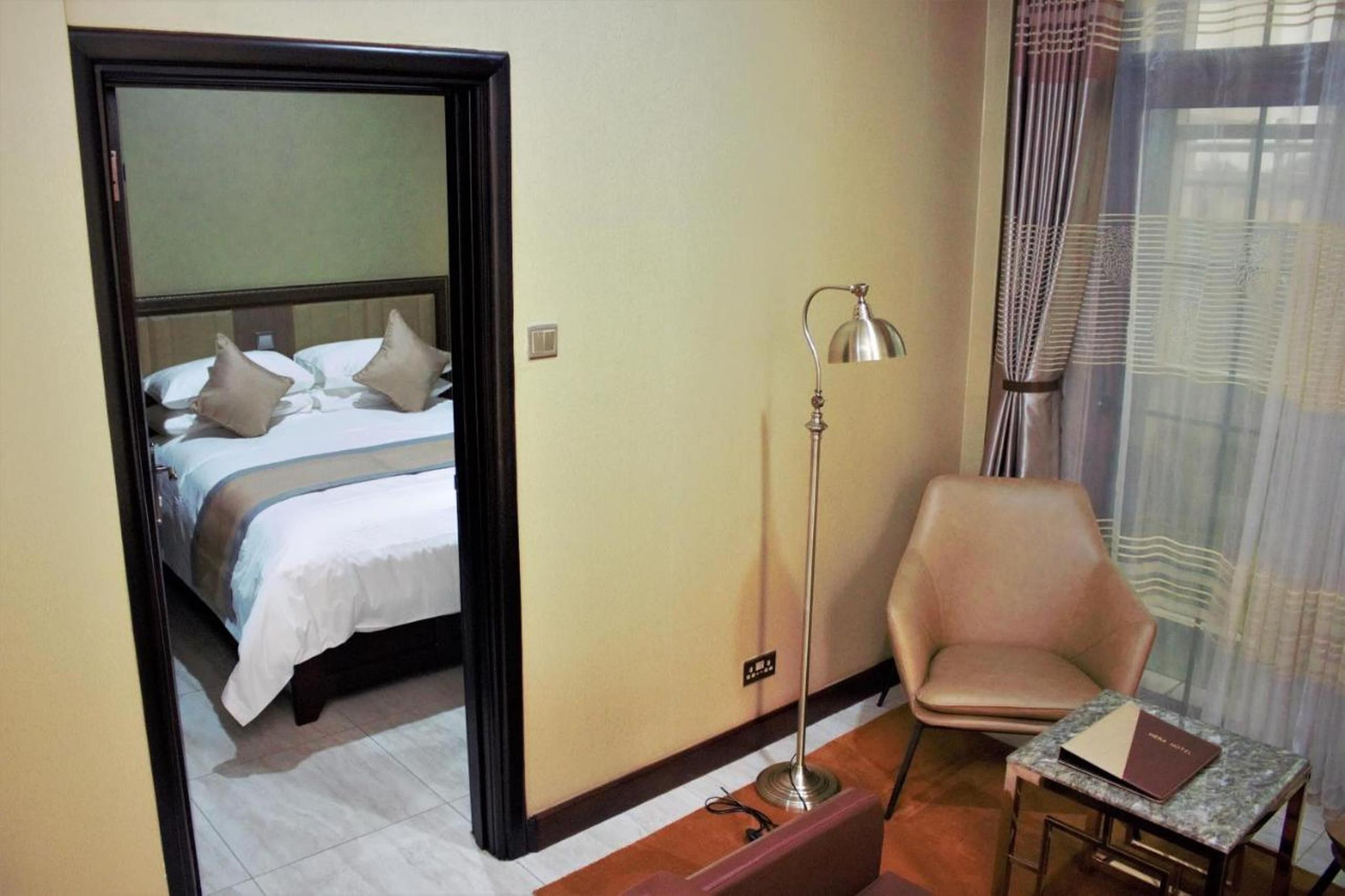 Una habitación de hotel con cama, una silla, una mesa y una lámpara de pie.