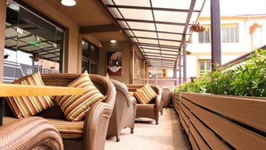 A covered outdoor seating area with wicker furniture and striped cushions. - Hera Hotel (Kampala)