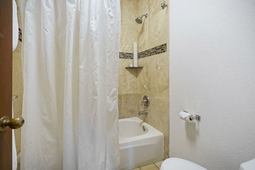 A bathroom with a bathtub, a toilet, and a shower curtain.
