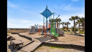 Children can play on the climbing frame, slide, and swing set in this outdoor playground area.