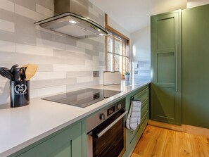 A modern kitchen with a white countertop, stainless steel appliances, and green cabinetry.