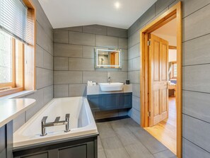 A modern bathroom with a large bathtub, a sink, and a mirror. - Bluebell Lodge-UK32958 (Ashford)