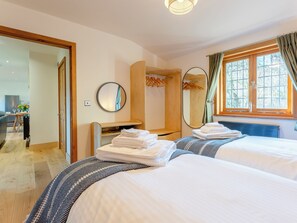 A hotel room with two beds, a desk, a mirror, and a window with curtains. - Bluebell Lodge-UK32958 (Ashford)