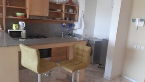 A kitchen with a microwave, kettle, and sink. There are two chairs and a washing machine. - AIRPORT to Comme à la maison 2, 5 minutes from the airport (Nouaceur)