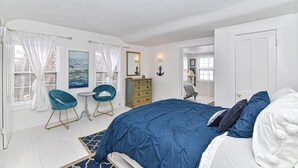 Une chambre à coucher avec un grand lit, une commode, deux chaises et une petite table.