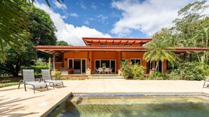 A house with a swimming pool, outdoor seating, and lush greenery. - Casa Tropical, Spacious 3 BR Home with Pool (Brasilito)